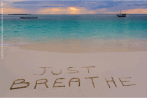 Strandaufnahme mit dem Schriftzug ‚Just Breathe‘ im Sand – Symbol für innere Ruhe und bewusste Atmung, die unser vegetatives Nervensystem unterstützt